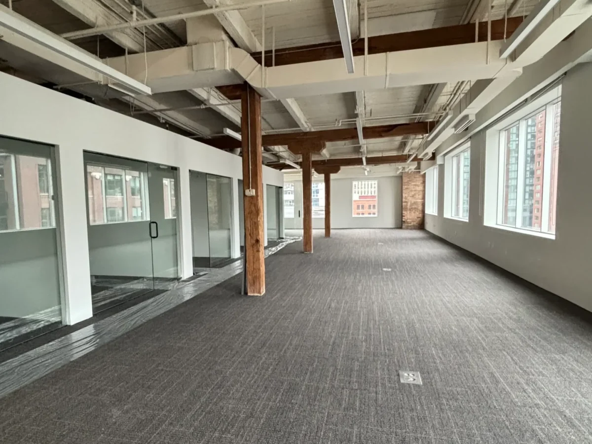 Spacious office interior featuring exposed beams, large windows, and carpeted flooring, highlighting tenant improvement electrical work by Flavin Electric in Chicago.